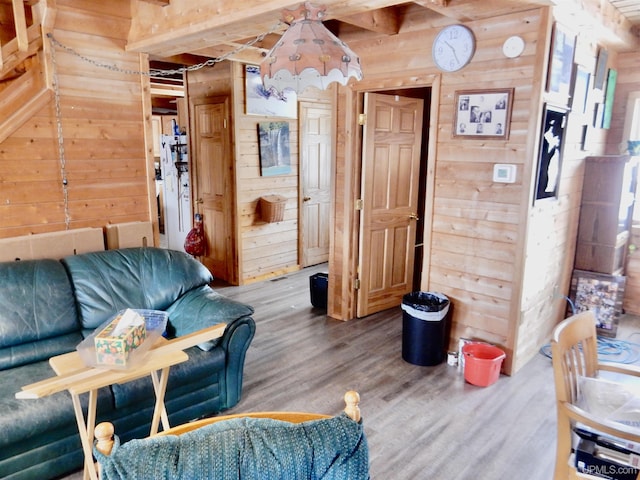 living area with beam ceiling, wood walls, and wood finished floors