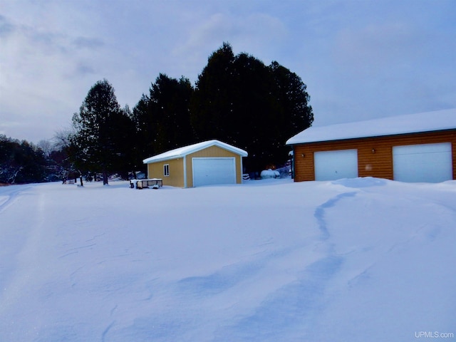 snow covered garage with a detached garage