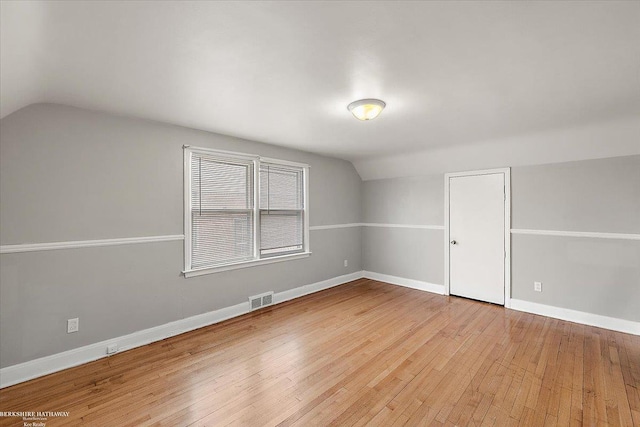 bonus room featuring vaulted ceiling, light wood-style flooring, visible vents, and baseboards