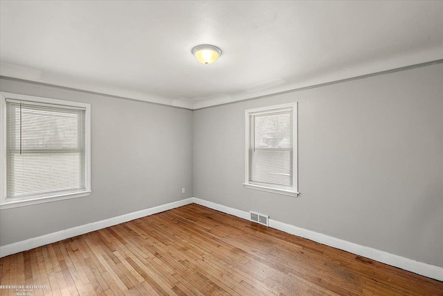 spare room featuring visible vents, baseboards, and wood finished floors