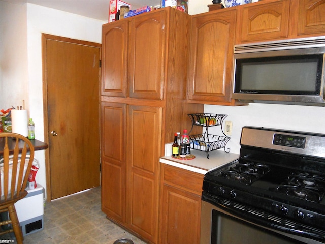 kitchen with stainless steel appliances, dark floors, light countertops, and brown cabinets