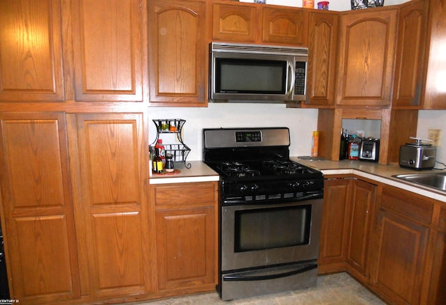 kitchen with stainless steel appliances, brown cabinets, and light countertops