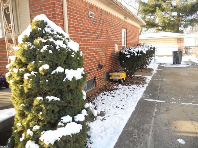 snow covered property with a garage and brick siding