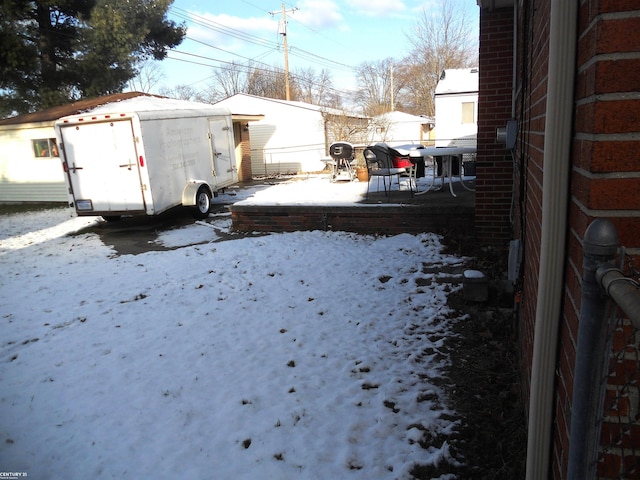 snowy yard featuring an outbuilding and a shed