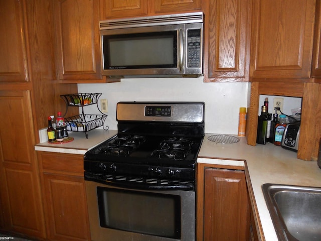 kitchen with brown cabinetry, stainless steel appliances, and light countertops