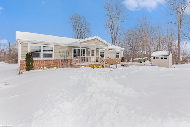 manufactured / mobile home with a storage unit, a porch, an outdoor structure, and brick siding