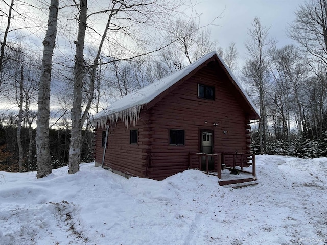 view of snowy exterior featuring log siding