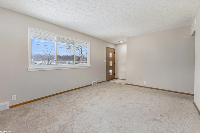 unfurnished room featuring visible vents, carpet flooring, a textured ceiling, and baseboards