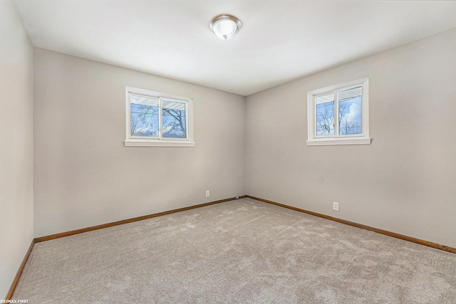 empty room with baseboards, a wealth of natural light, and light colored carpet