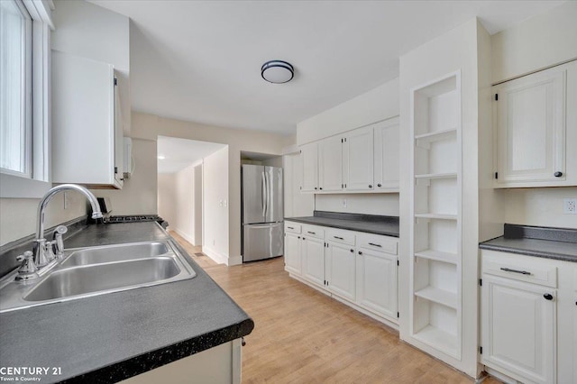 kitchen with dark countertops, freestanding refrigerator, and white cabinetry