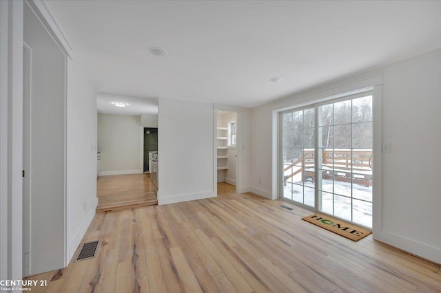 unfurnished room featuring light wood-style flooring, visible vents, and baseboards