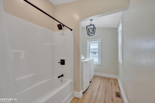 full bathroom with shower / bath combination, visible vents, washing machine and dryer, wood finished floors, and baseboards