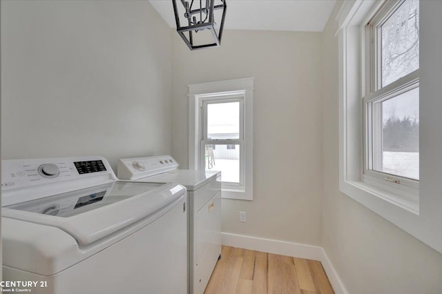 laundry room with laundry area, separate washer and dryer, light wood-type flooring, and baseboards