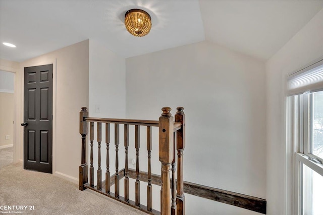 interior space with lofted ceiling, baseboards, an upstairs landing, and light colored carpet