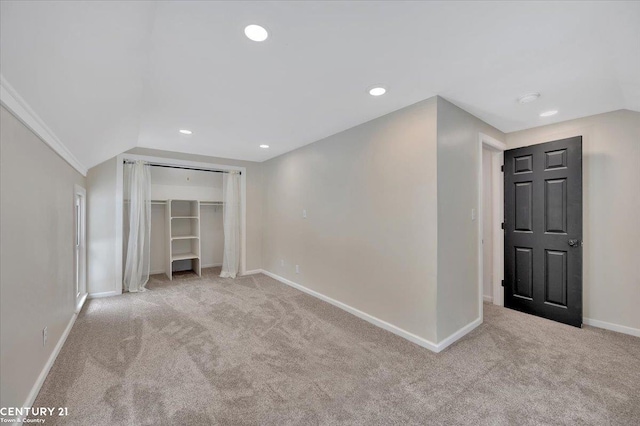 empty room featuring light carpet, recessed lighting, lofted ceiling, and baseboards