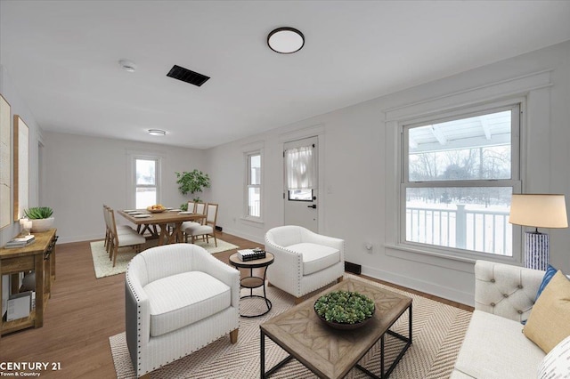 living area with wood finished floors, visible vents, and baseboards