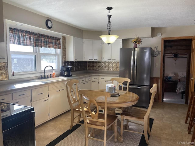 kitchen with white cabinetry, pendant lighting, a sink, and freestanding refrigerator