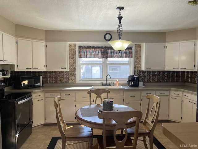 kitchen featuring white cabinets, a sink, hanging light fixtures, and black appliances