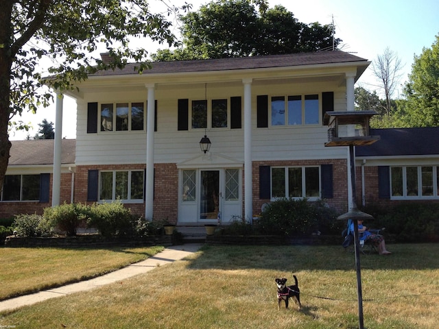 neoclassical / greek revival house featuring a front yard, a chimney, and brick siding