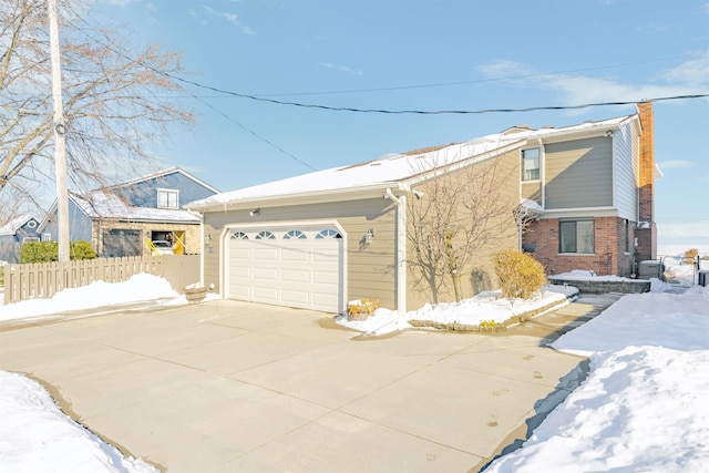 view of front of home featuring concrete driveway, brick siding, an attached garage, and fence