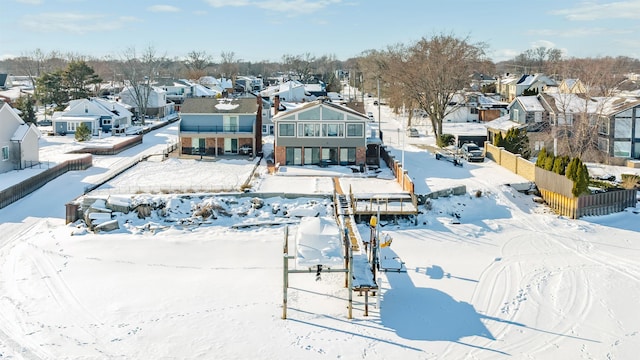 snow covered back of property with a residential view and fence