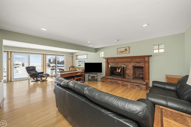 living area with recessed lighting, a fireplace, and light wood-style floors