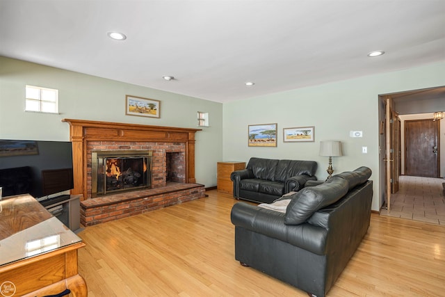 living area with a fireplace, light wood-style flooring, and recessed lighting