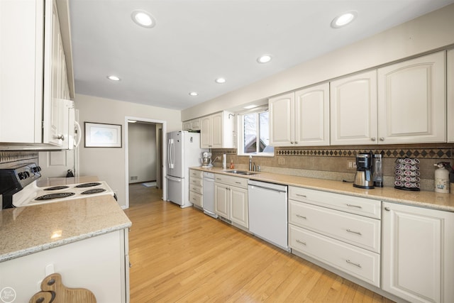 kitchen with white appliances, white cabinets, and a sink