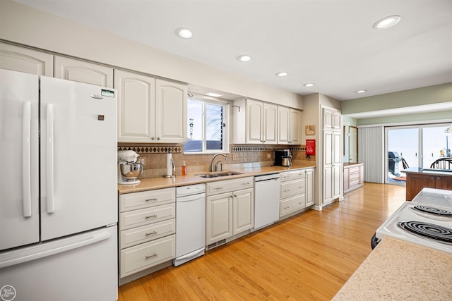 kitchen with white appliances, light countertops, a sink, and white cabinetry