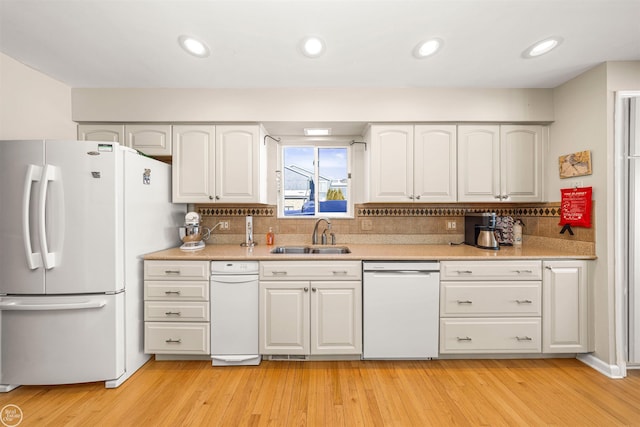 kitchen featuring white cabinets, white appliances, light countertops, and a sink