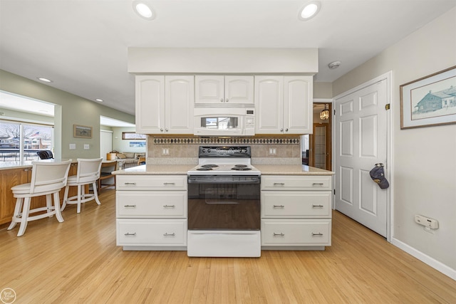 kitchen featuring white appliances, light wood-style floors, white cabinets, and decorative backsplash