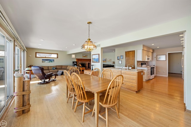 dining room with light wood-type flooring, a brick fireplace, visible vents, and recessed lighting