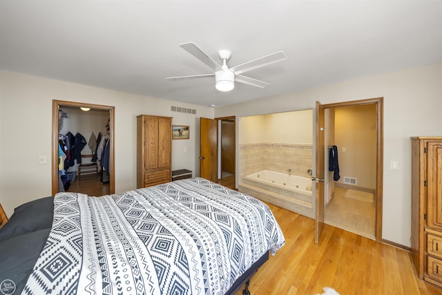 bedroom featuring light wood-style floors, visible vents, a walk in closet, and a closet