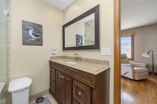 bathroom with wood finished floors, vanity, toilet, and baseboards