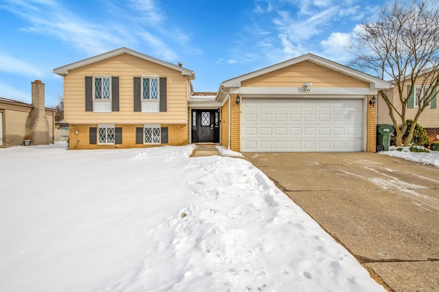 tri-level home with driveway, brick siding, and an attached garage