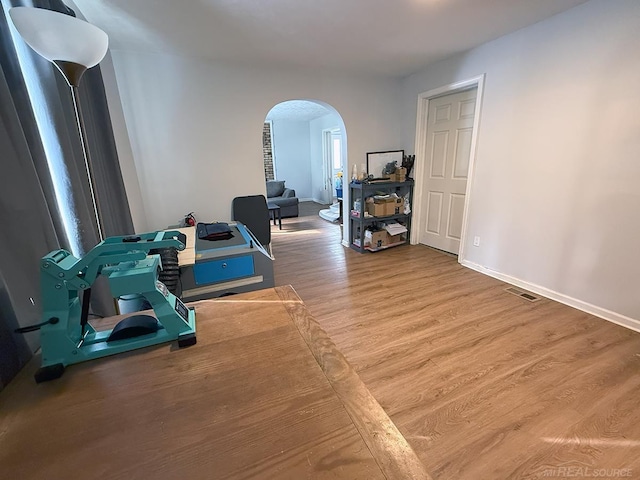 interior space with arched walkways, wood finished floors, visible vents, and baseboards