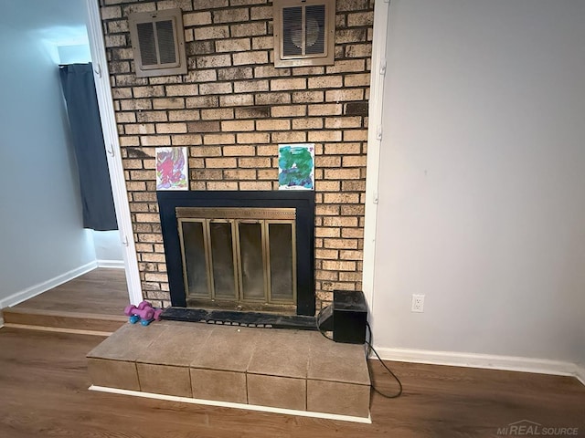 interior details with visible vents, a fireplace, baseboards, and wood finished floors