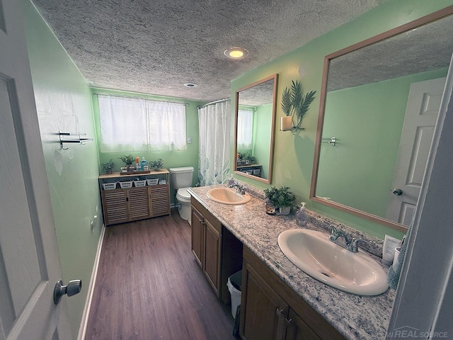 bathroom featuring double vanity, a sink, toilet, and wood finished floors