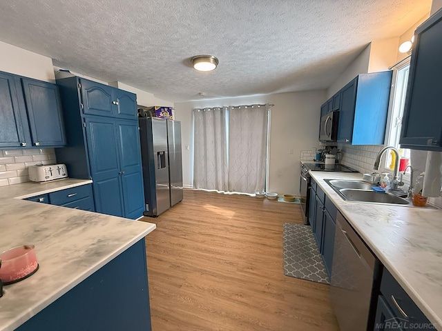 kitchen featuring blue cabinets, appliances with stainless steel finishes, light countertops, and a sink