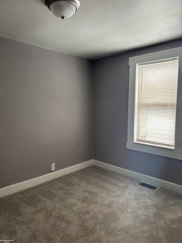 unfurnished room with carpet, visible vents, and baseboards