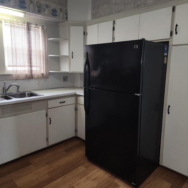 kitchen featuring freestanding refrigerator, light countertops, white cabinetry, open shelves, and a sink