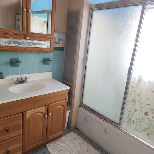 full bath featuring shower / bath combination with glass door, tile walls, and vanity