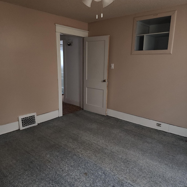 unfurnished room with baseboards, visible vents, dark colored carpet, and a ceiling fan