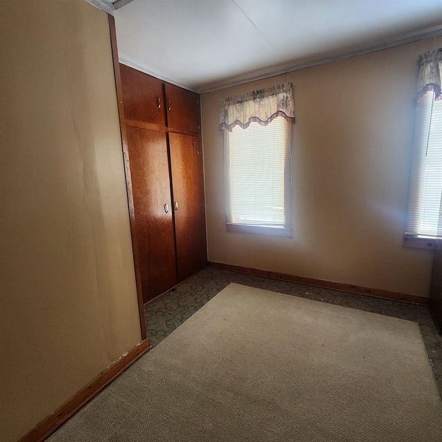 unfurnished bedroom with a closet, light carpet, and baseboards