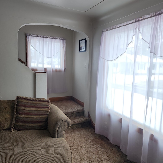 carpeted bedroom featuring multiple windows and arched walkways