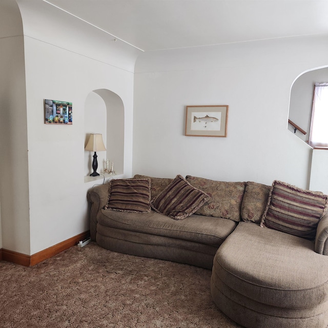 living area with arched walkways, carpet floors, and baseboards