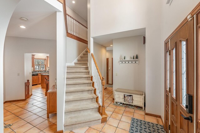 entrance foyer with stairs, a high ceiling, and light tile patterned floors