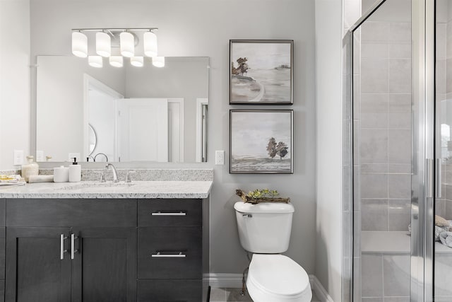 full bath with toilet, a shower stall, baseboards, and vanity