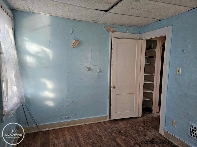 unfurnished room featuring baseboards, visible vents, dark wood finished floors, and a drop ceiling