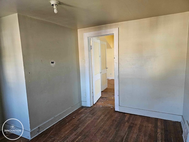 unfurnished room with dark wood-type flooring and baseboards